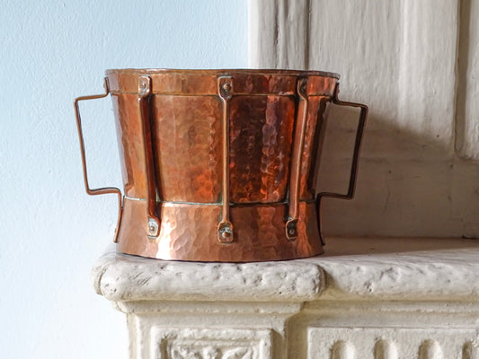 French antique copper ferrat with hammered copper body and two handles. Displayed on a country house fireplace.