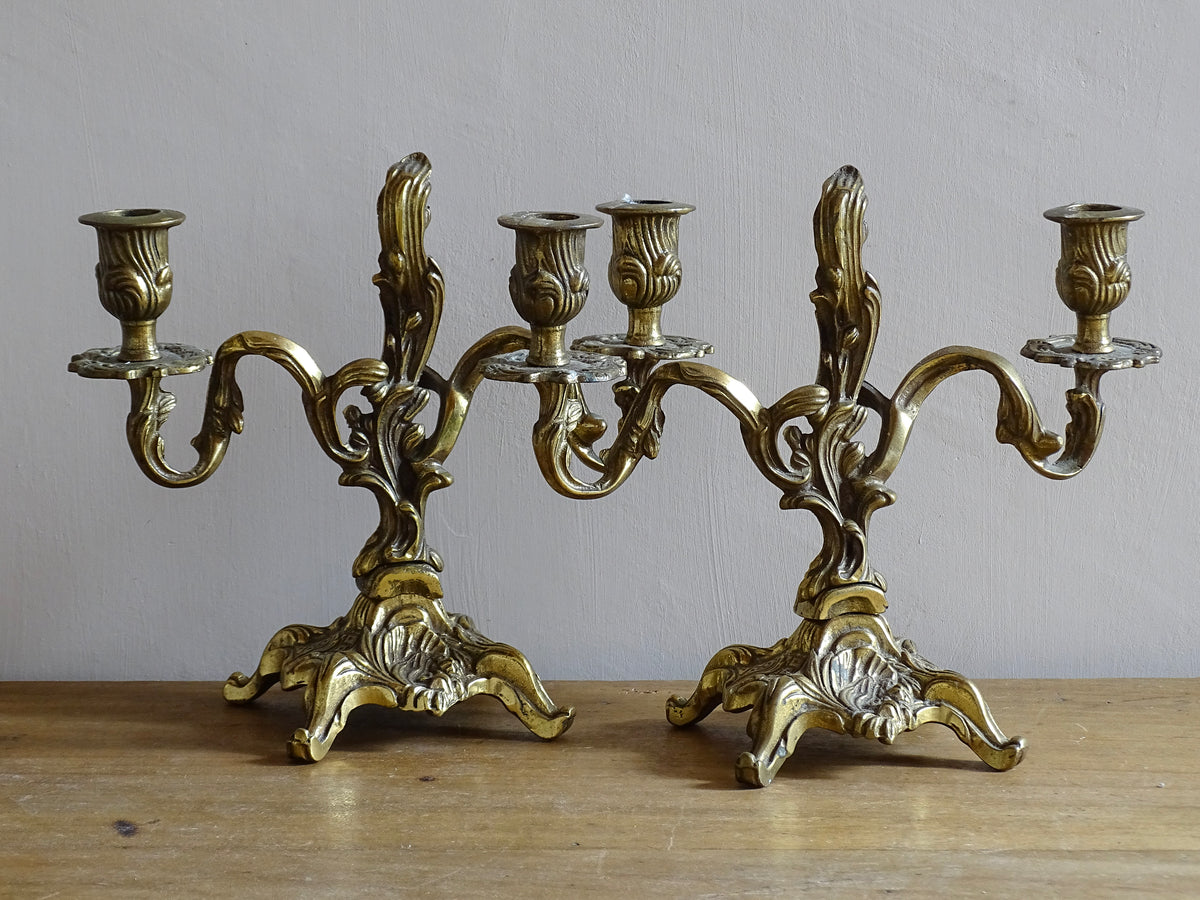 Pair of French antique brass candelabras in a rococo style. Early 20th century antique candelabras with space for two tapered candlesticks. Brass candle holders for dining table decor or living room decor.