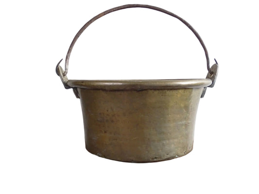 French antique brass cauldron with a hammered brass body and wrought iron handle, brass cooking pot ideal for farmhouse kitchen decor or rustic home decor, displayed on a wooden surface.
