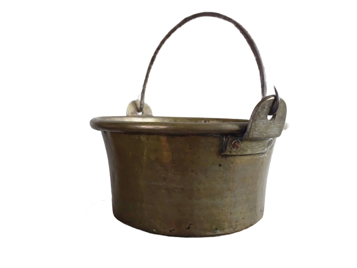 French antique brass cauldron with a hammered brass body and wrought iron handle, brass cooking pot ideal for farmhouse kitchen decor or rustic home decor, displayed on a wooden surface.