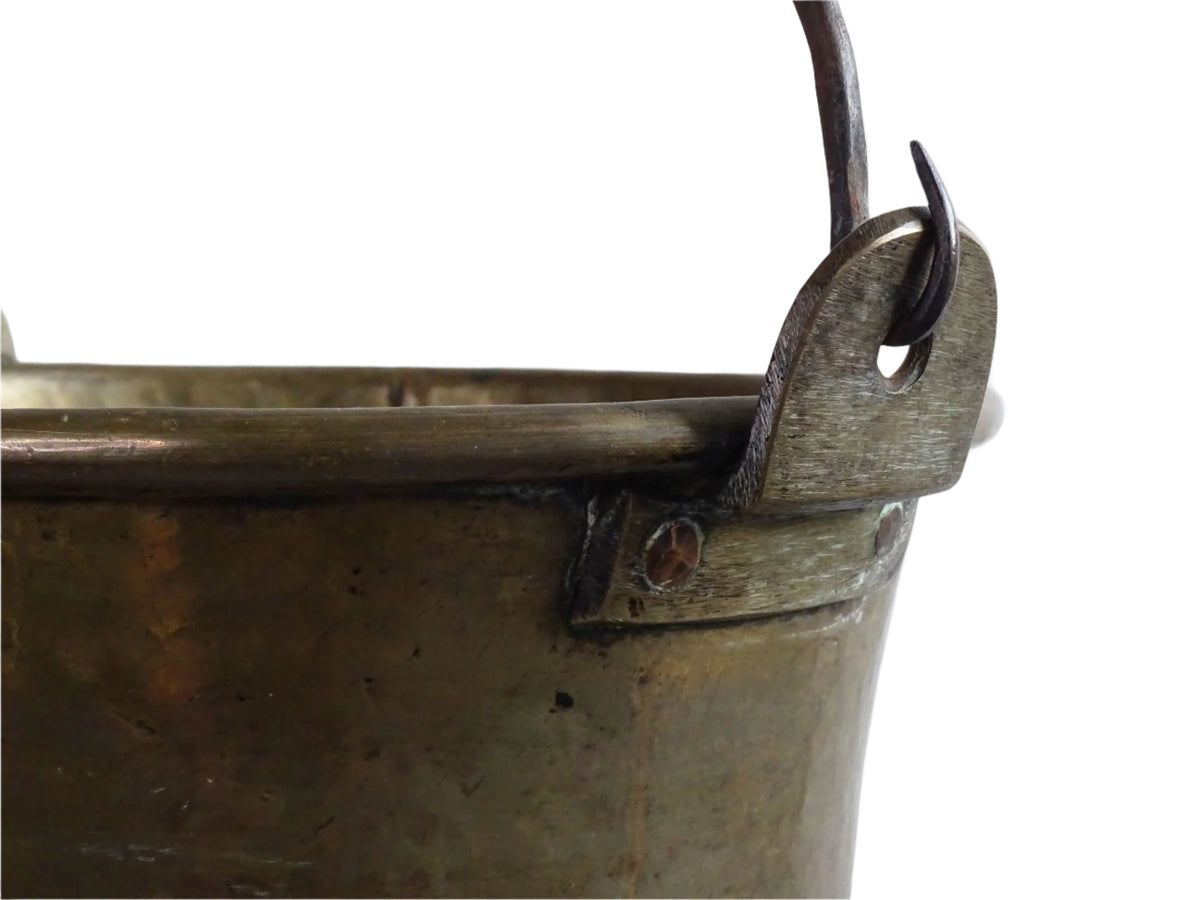 French antique brass cauldron with a hammered brass body and wrought iron handle, brass cooking pot ideal for farmhouse kitchen decor or rustic home decor, displayed on a wooden surface.