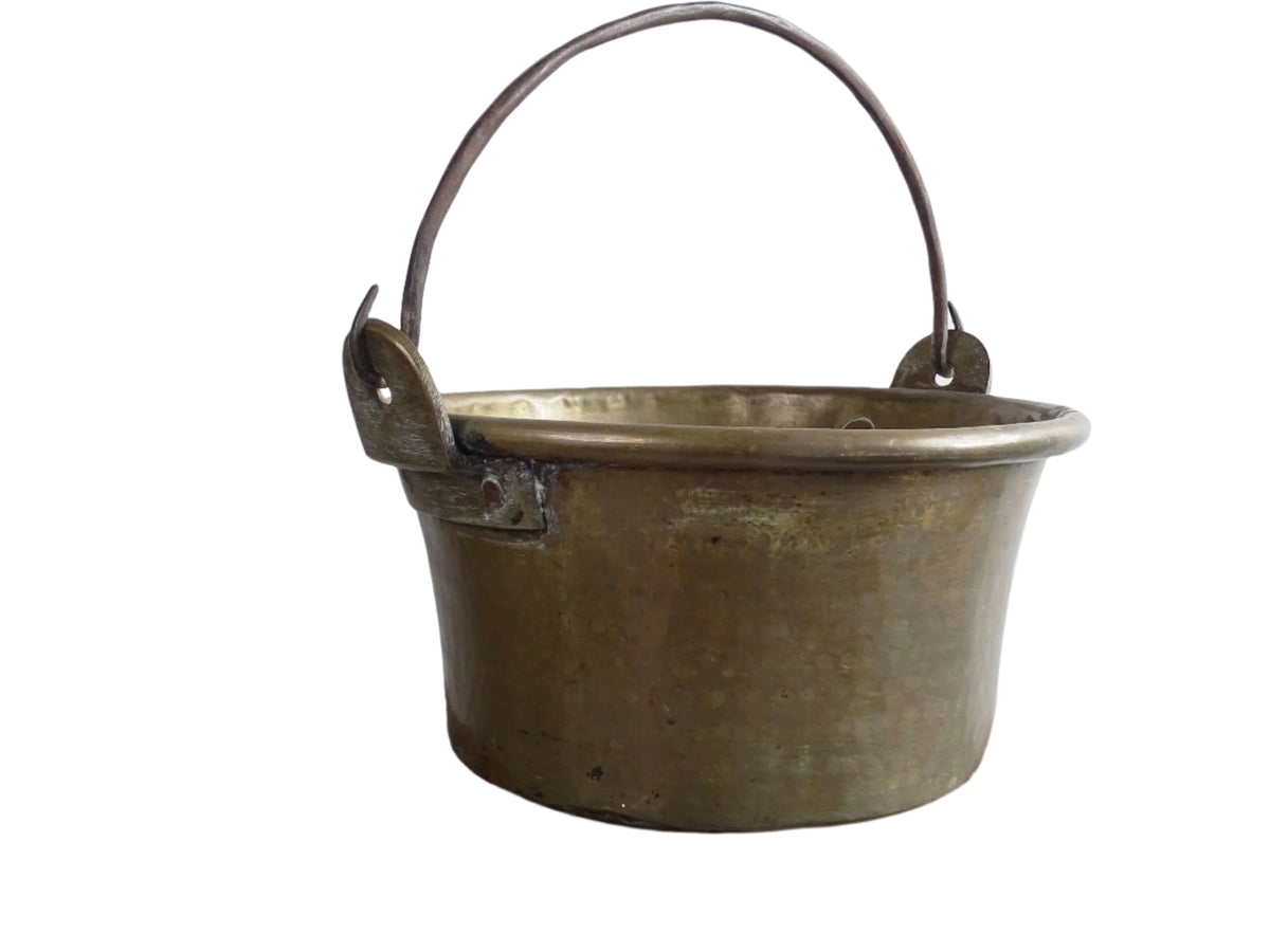 French antique brass cauldron with a hammered brass body and wrought iron handle, brass cooking pot ideal for farmhouse kitchen decor or rustic home decor, displayed on a wooden surface.