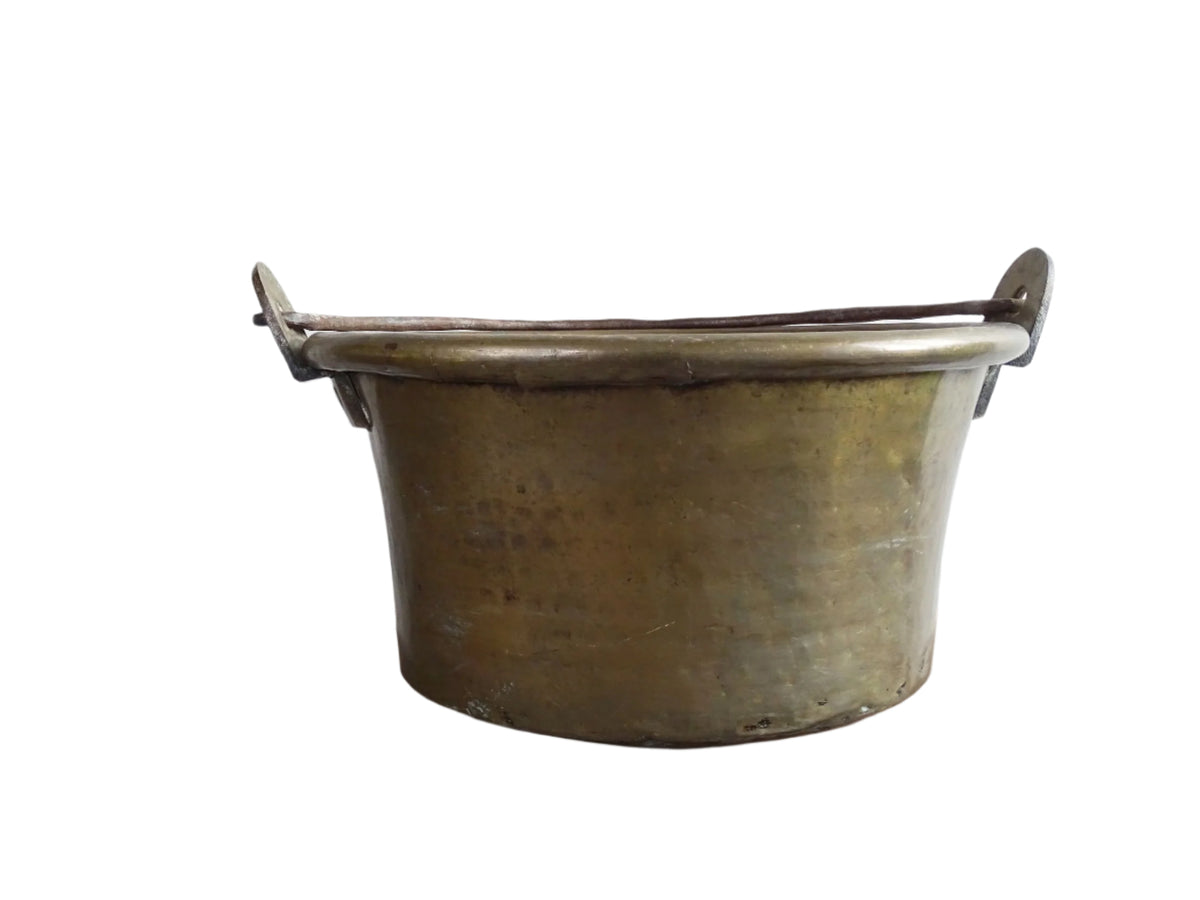 French antique brass cauldron with a hammered brass body and wrought iron handle, brass cooking pot ideal for farmhouse kitchen decor or rustic home decor, displayed on a wooden surface.