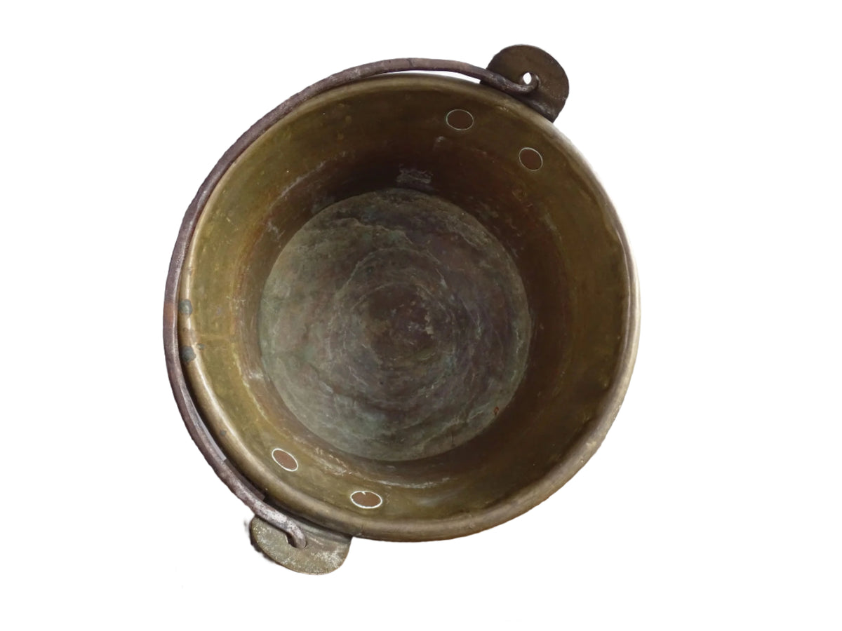 French antique brass cauldron with a hammered brass body and wrought iron handle, brass cooking pot ideal for farmhouse kitchen decor or rustic home decor, displayed on a wooden surface.