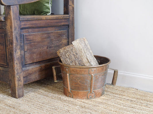 Antique hammered copper bucket from France with aged surface and riveted detail, once used to carry water, shown on a white background.