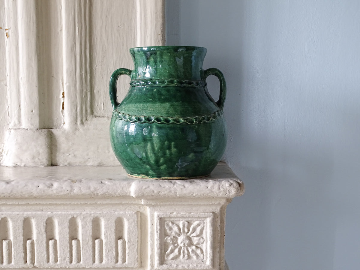French vintage ceramic vase with green glaze pictured on a country house fireplace