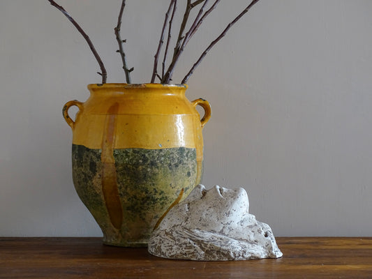 French antique plaster head alongside a yellow confit pot with branches.