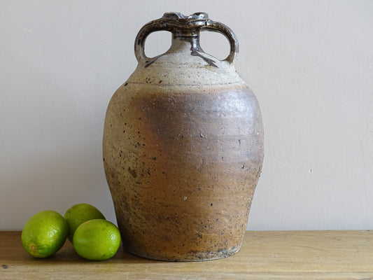 French antique pottery pitcher for a rustic farmhouse kitchen. Earthenware pottery pitcher with brown top, two handles and red-tone body