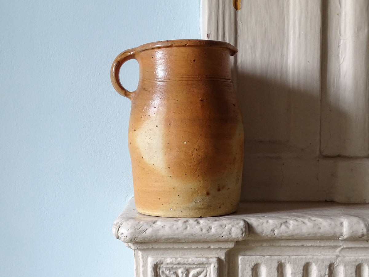 Large French antique ceramic milk jug with a brown glaze, pictured on a country house fireplace