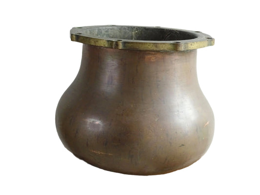 A large antique copper cauldron with a thick brass rim featuring evenly spaced holes, displayed on a rustic wooden surface. The cauldron has a weathered patina, showcasing its aged character.