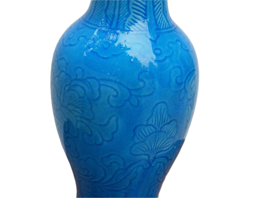 A Chinese antique porcelain table lamp in peacock blue with a raised flower and foliage design, set on a carved wooden base. Ideal for antique lamp collectors, bedroom decor, or as a vintage statement piece for living room interiors.