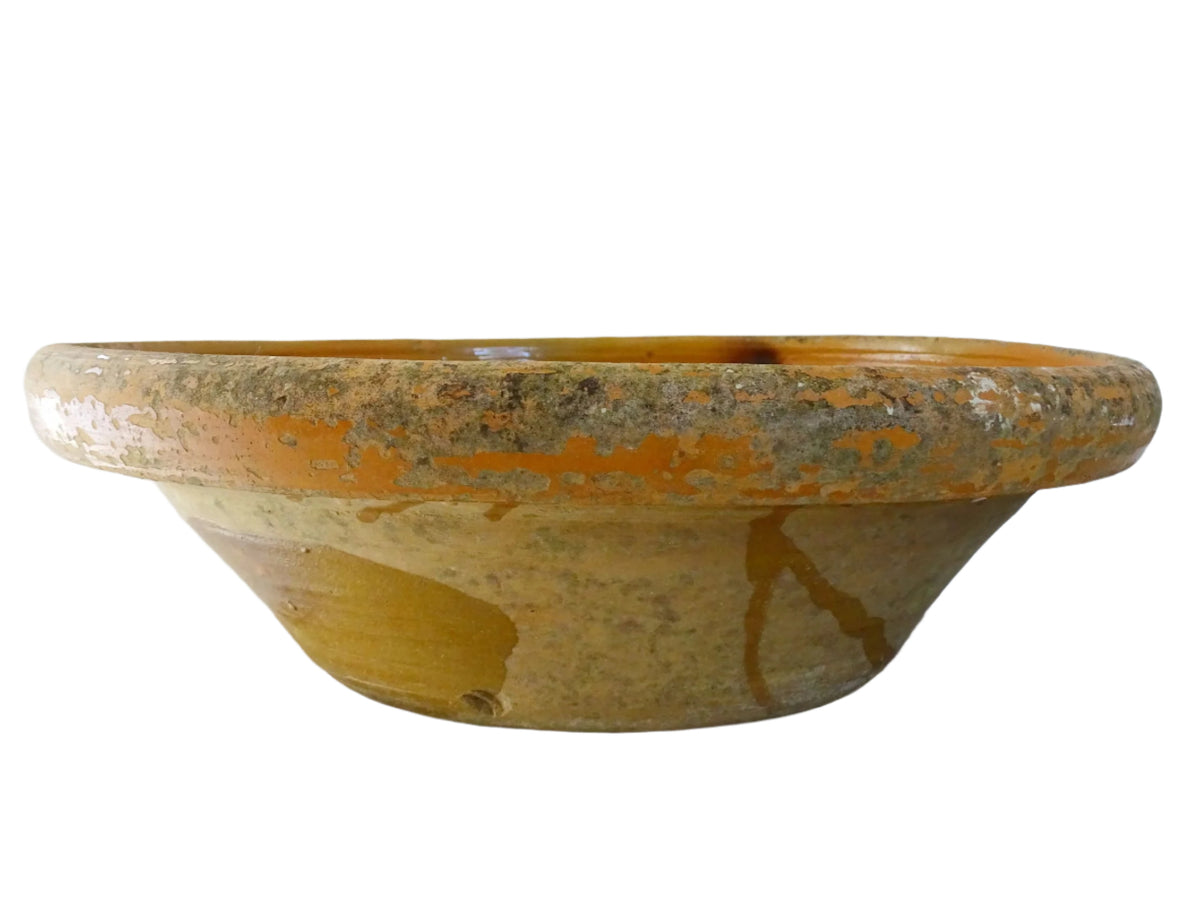Large French antique pottery bowl with an orange glaze and blushes of green and blue. Timeworn terracotta bowl or basin has two holes in the bottom. Pottery colander or pottery strainer.