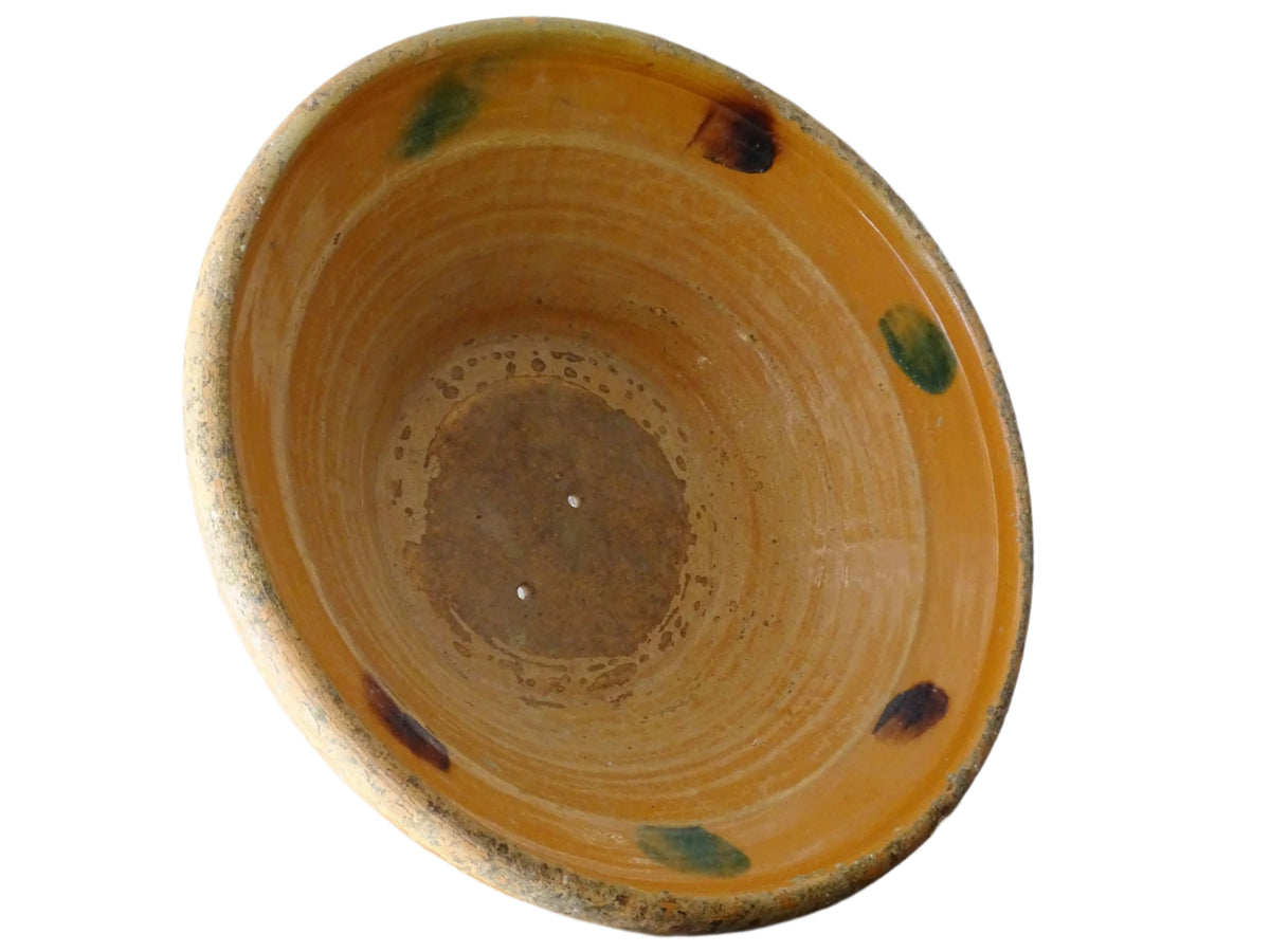 Large French antique pottery bowl with an orange glaze and blushes of green and blue. Timeworn terracotta bowl or basin has two holes in the bottom. Pottery colander or pottery strainer.