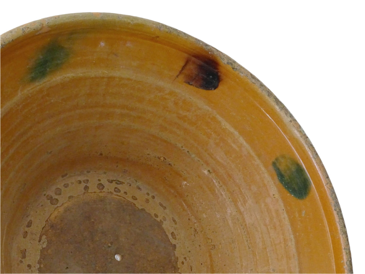 Large French antique pottery bowl with an orange glaze and blushes of green and blue. Timeworn terracotta bowl or basin has two holes in the bottom. Pottery colander or pottery strainer.