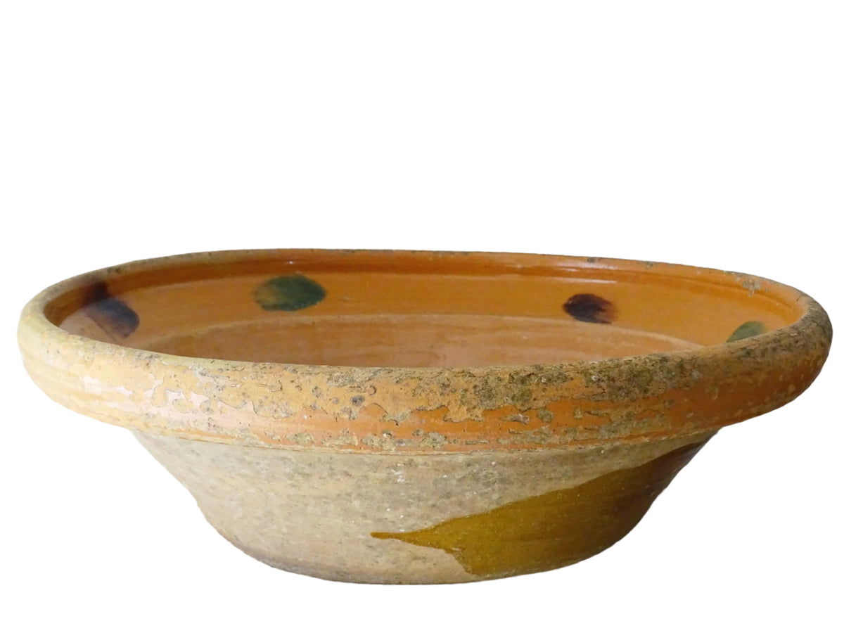 Large French antique pottery bowl with an orange glaze and blushes of green and blue. Timeworn terracotta bowl or basin has two holes in the bottom. Pottery colander or pottery strainer.