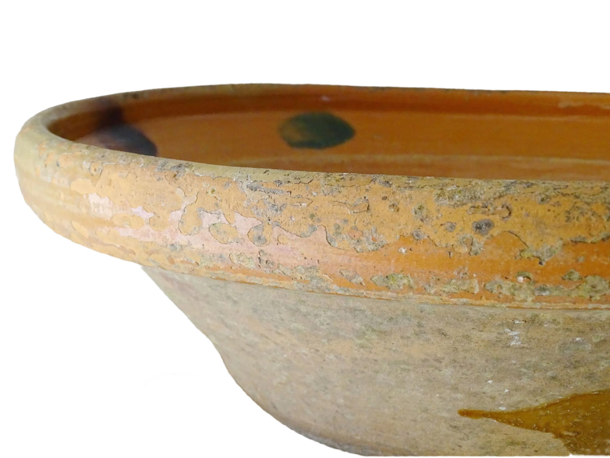 Large French antique pottery bowl with an orange glaze and blushes of green and blue. Timeworn terracotta bowl or basin has two holes in the bottom. Pottery colander or pottery strainer.