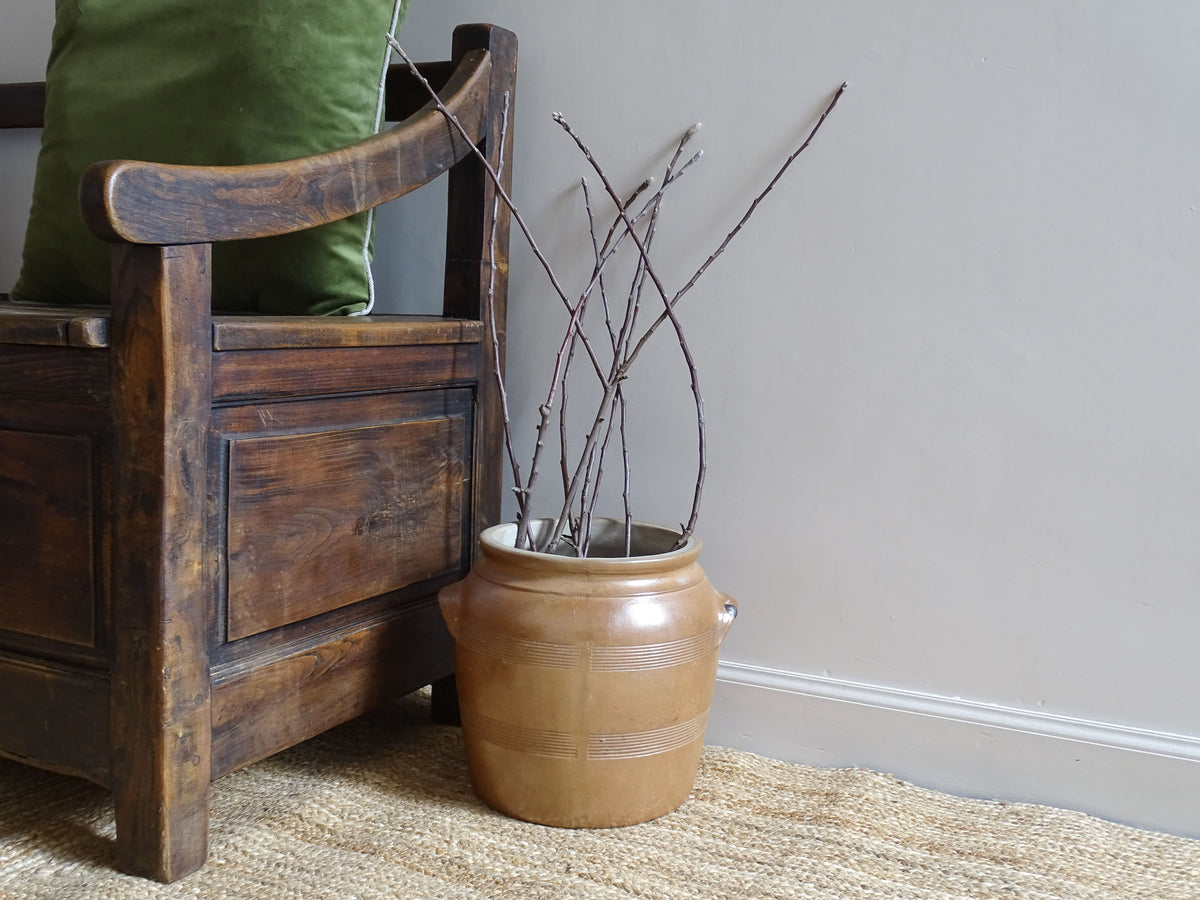 French antique stoneware cache pot or confit jar with a brown glaze, filled with branches.