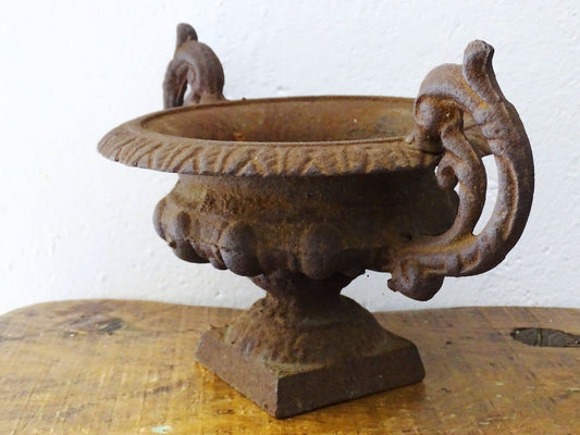 French antique cast iron urn planter with two handles with rusted red tones. Medici urn planter.
