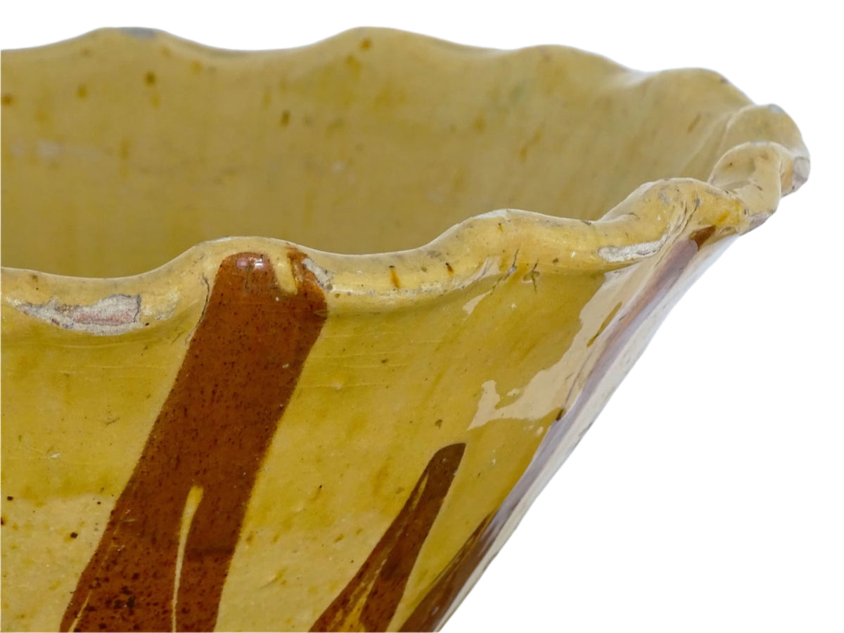 French antique terracotta bowl with yellow glaze, this earthenware basin has sweeps of a red-brown tone to the body and a crimped, pie crust style edge.