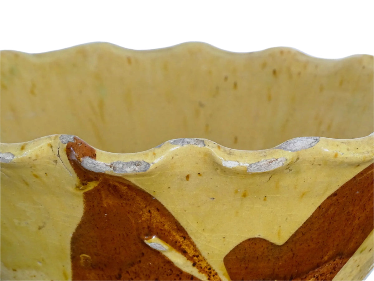 French antique terracotta bowl with yellow glaze, this earthenware basin has sweeps of a red-brown tone to the body and a crimped, pie crust style edge.