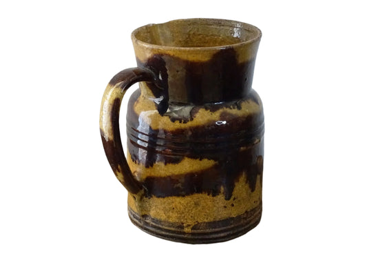 Rustic French antique ceramic jug with a brown drip glaze on a deep mustard colour background. Pottery jug from Dieulefit with a side spout. Rustic French pottery for a French farmhouse aesthetic.