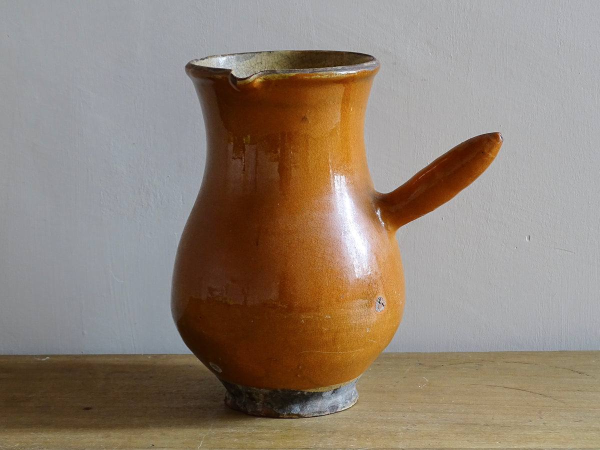 French antique terracotta jug with red glaze exterior and yellow glaze interior. Antique pottery pitcher with side handle and patina.
