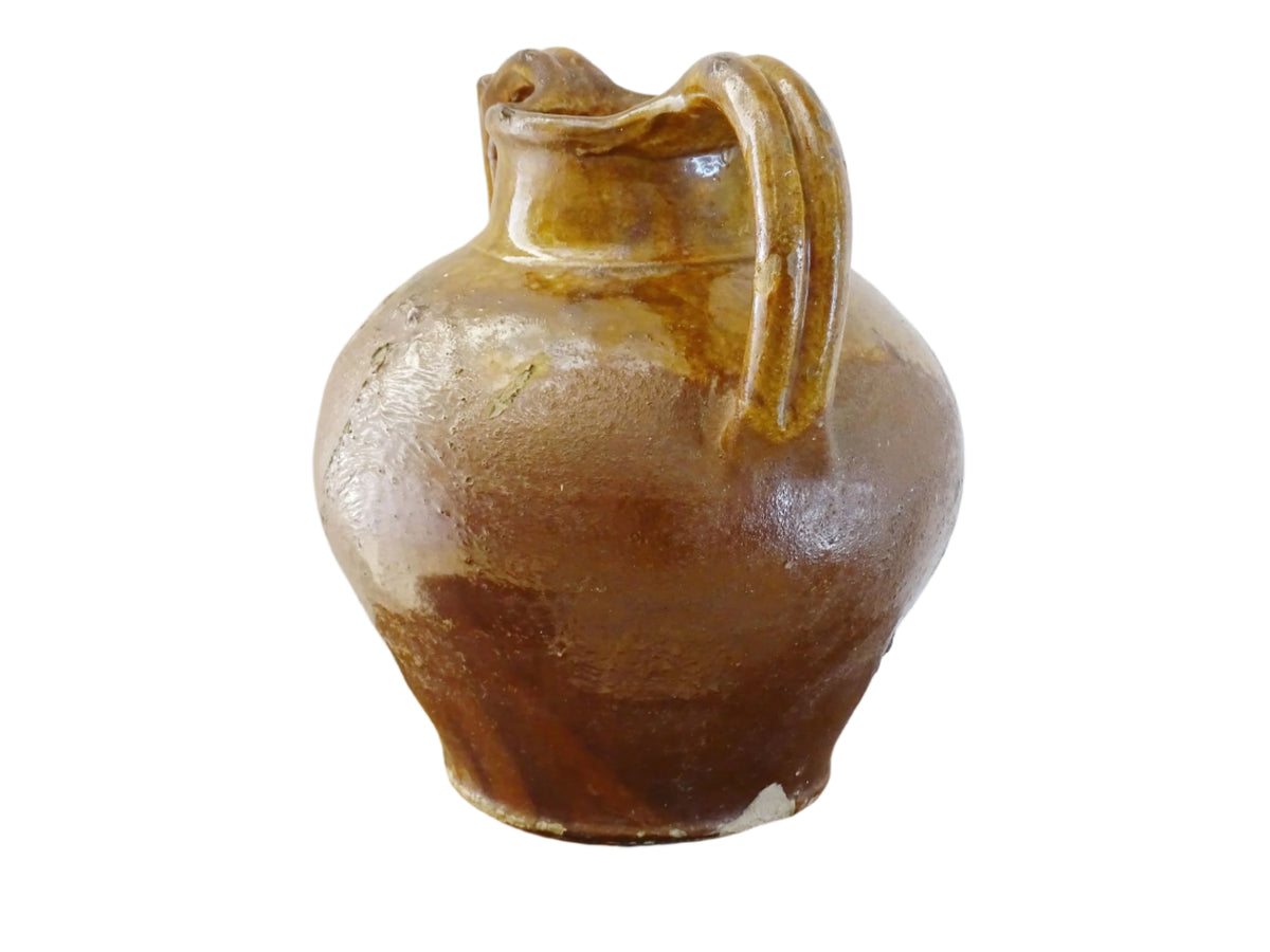 French antique pottery orjol or cruche with a golden caramel and yellow glaze. Glazed antique terracotta pitcher has two handles and a spout with a rounded body. Earthenware pottery for an antique French farmhouse style aesthetic.