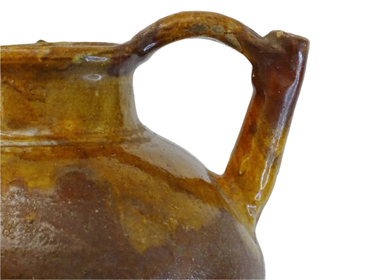 French antique pottery orjol or cruche with a golden caramel and yellow glaze. Glazed antique terracotta pitcher has two handles and a spout with a rounded body. Earthenware pottery for an antique French farmhouse style aesthetic.