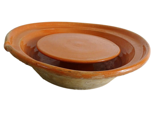 French antique pottery cheese strainer or faisseller. Shaped like a French tian bowl with a stand in the middle and a lip to the edge. Rustic French antique pottery bowl with an orange glaze. Glazed earthenware cheese drainer.