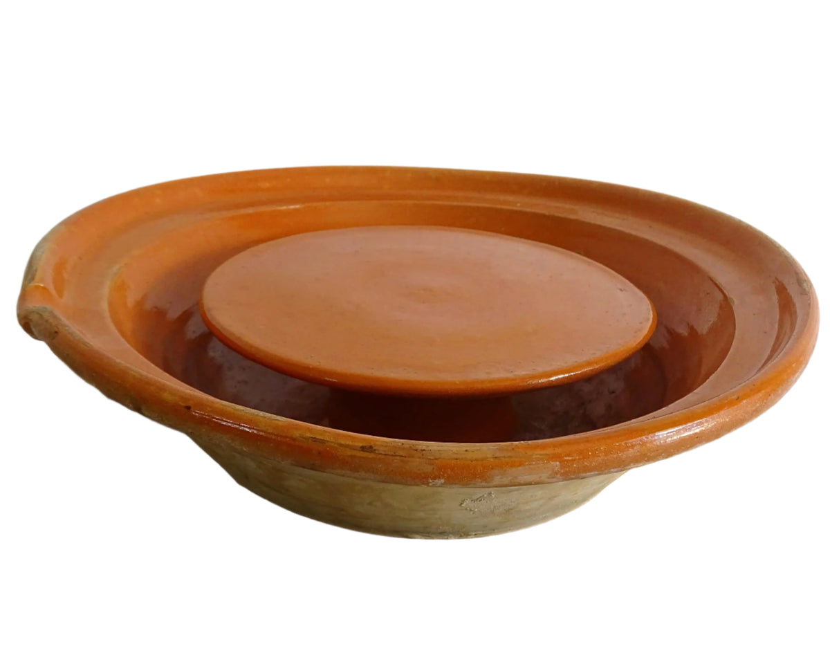 French antique pottery cheese strainer or faisseller. Shaped like a French tian bowl with a stand in the middle and a lip to the edge. Rustic French antique pottery bowl with an orange glaze. Glazed earthenware cheese drainer.