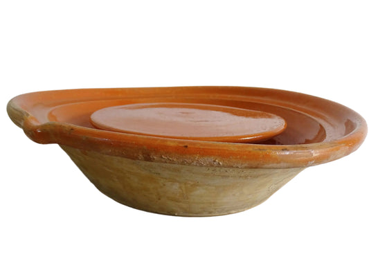 French antique pottery cheese strainer or faisseller. Shaped like a French tian bowl with a stand in the middle and a lip to the edge. Rustic French antique pottery bowl with an orange glaze. Glazed earthenware cheese drainer.