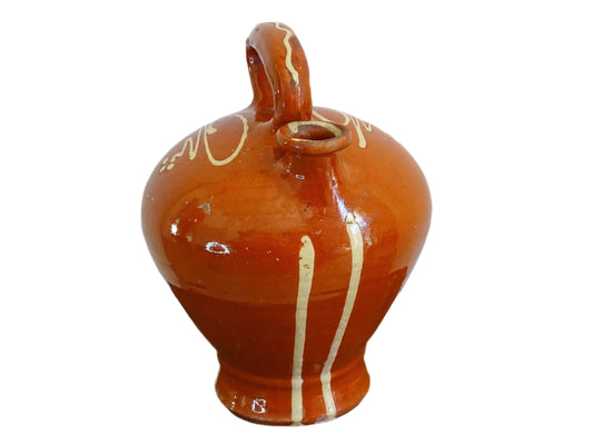 Rustic French antique pottery cruche or gargoulette with a deep red glaze and yellow stripe detailing. The body of this terracotta pitcher is a rounded shape with a handle to the top and two spouts. Glazed pottery water jug for a Provençal style farmhouse table.