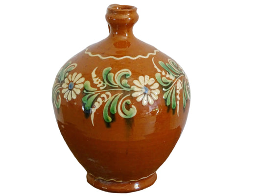 French vintage terracotta pitcher glazed in orange and decorated with hand-painted flowers. Pottery jug with a rounded shape with a handle and spout. Folk pottery cruche for folk art shelf decor.