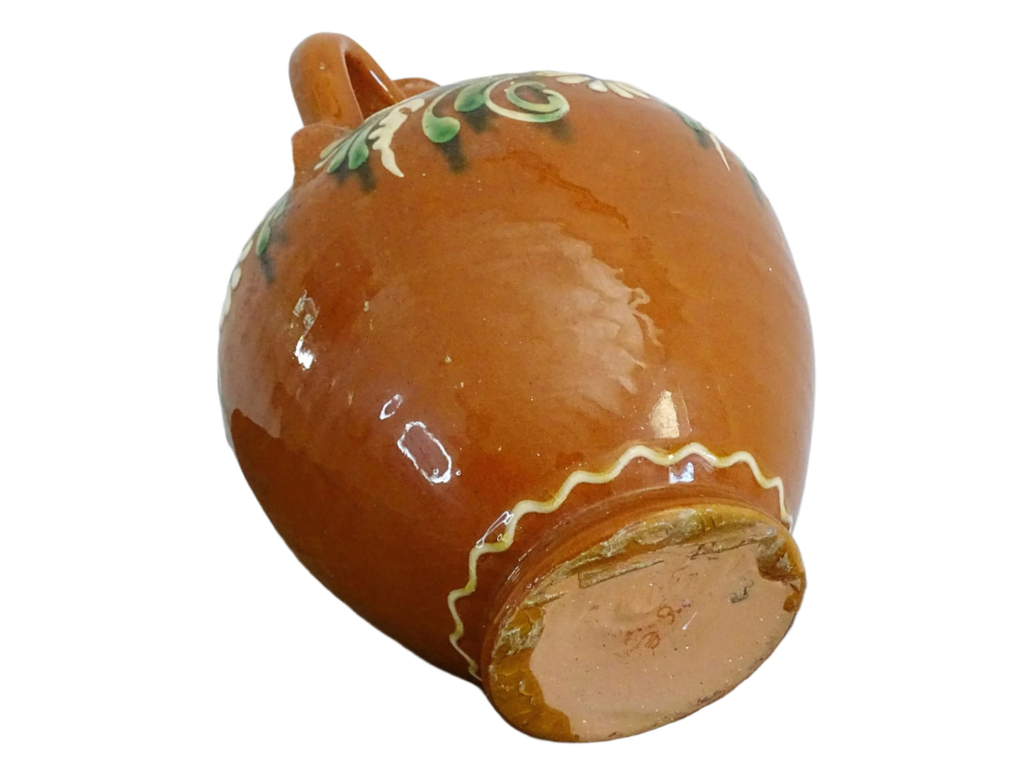 French vintage terracotta pitcher glazed in orange and decorated with hand-painted flowers. Pottery jug with a rounded shape with a handle and spout. Folk pottery cruche for folk art shelf decor.