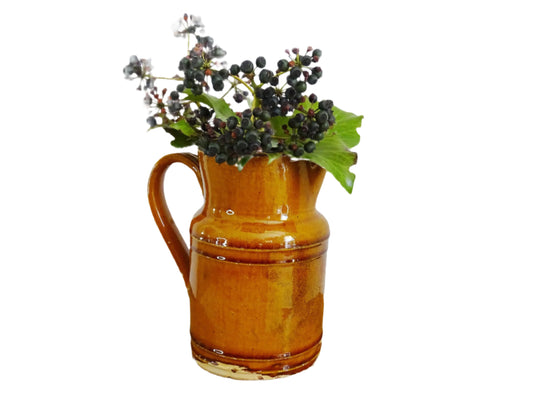 Rustic French antique pottery jug with an orange glaze. Glazed ceramic pitcher from Savoie. Savoyard pottery jug with a handle and spout.