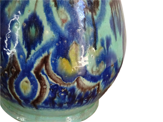 A French vintage ceramic vase lamp base with a bold, multicolored glaze in deep blue, green, and yellow. The organic, dripping pattern covers the surface, giving it a fluid, textured look. The vase has a rounded body that tapers towards a narrower neck, fitted with a brass lamp attachment. It rests on a slightly elevated base.
