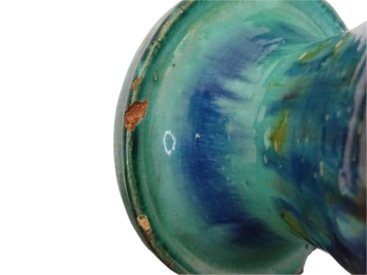 A French vintage ceramic vase lamp base with a bold, multicolored glaze in deep blue, green, and yellow. The organic, dripping pattern covers the surface, giving it a fluid, textured look. The vase has a rounded body that tapers towards a narrower neck, fitted with a brass lamp attachment. It rests on a slightly elevated base.