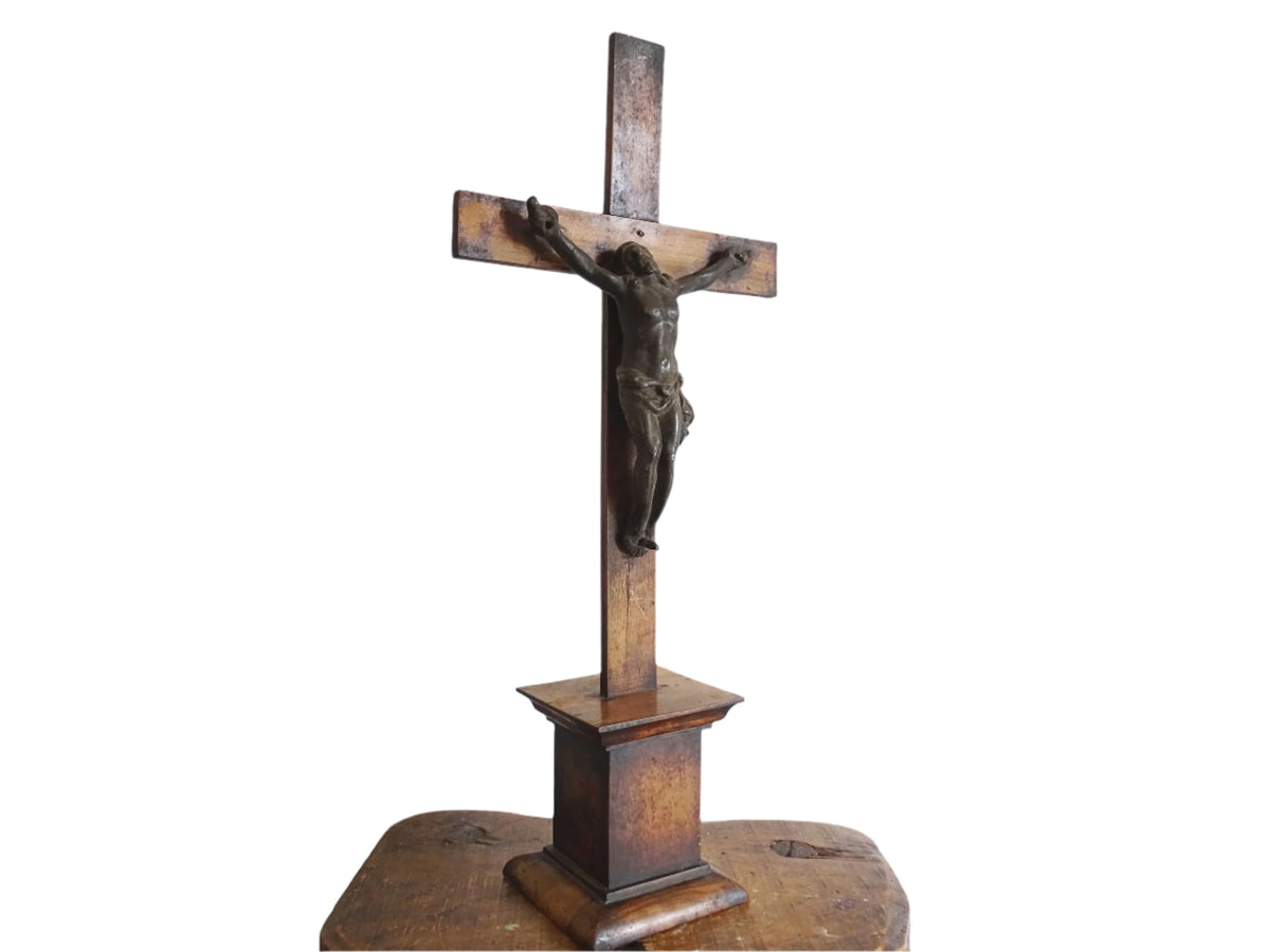 A French antique altar crucifix featuring a wooden cross with a spelter figure of Christ, mounted on a tiered wooden base. The wood has a rich patina.