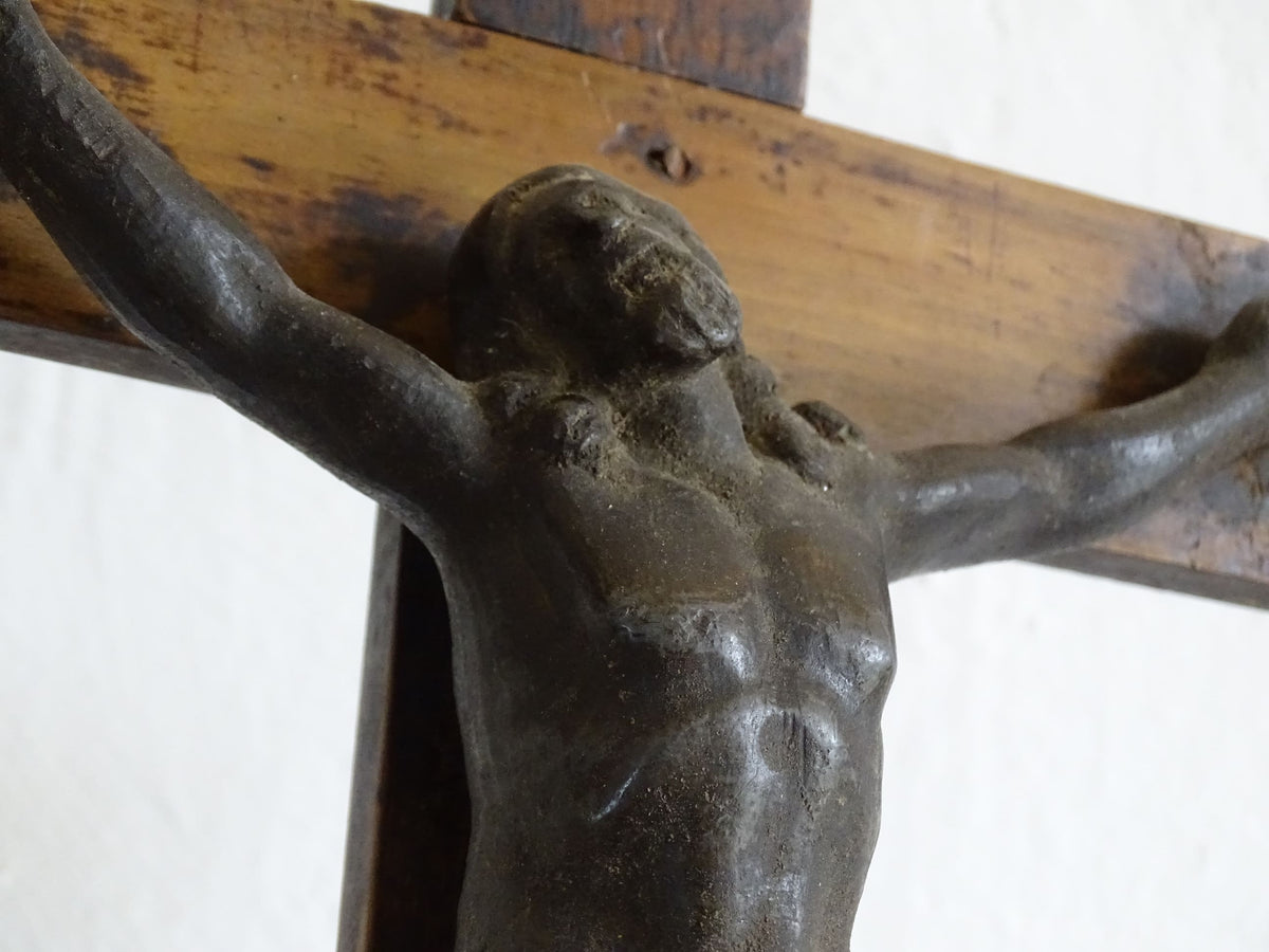 A French antique altar crucifix featuring a wooden cross with a spelter figure of Christ, mounted on a tiered wooden base. The wood has a rich patina.