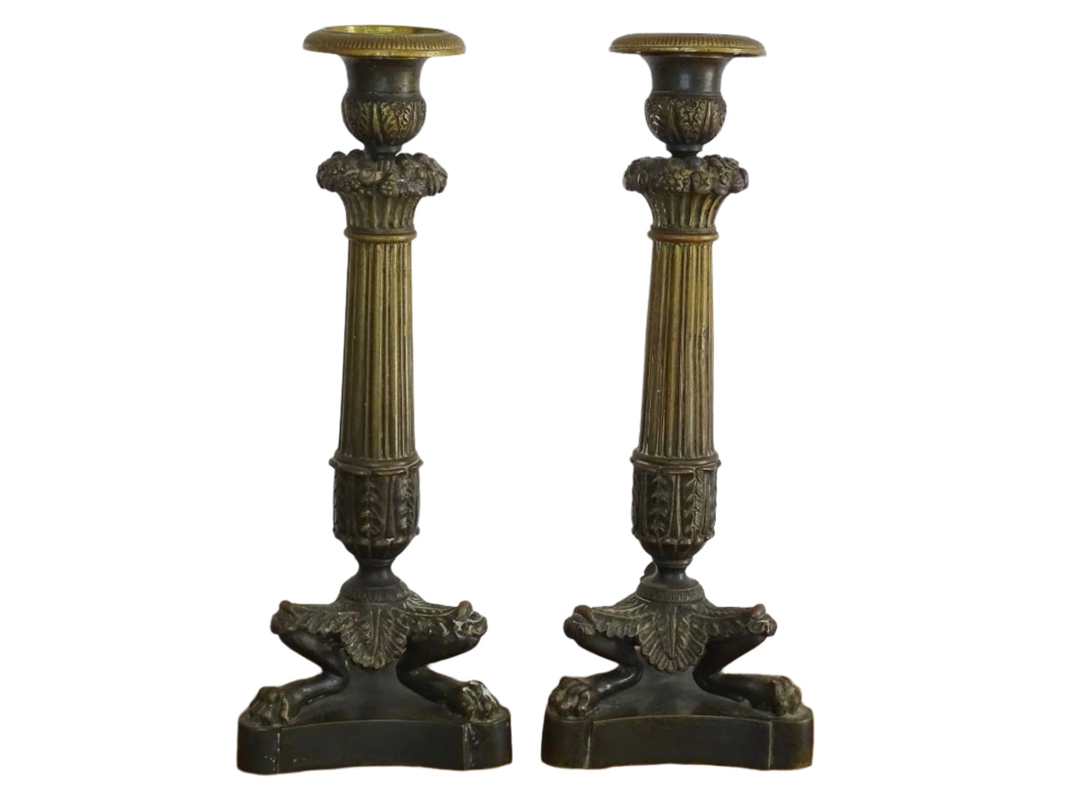 French antique bronze candle holders. French restoration period candlesticks are on a tripod base with lion paw feet and acanthus leaves. Acanthus leaves and various fruits and berries adorn the top of the reeded columns.