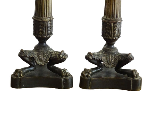 French antique bronze candle holders. French restoration period candlesticks are on a tripod base with lion paw feet and acanthus leaves. Acanthus leaves and various fruits and berries adorn the top of the reeded columns.
