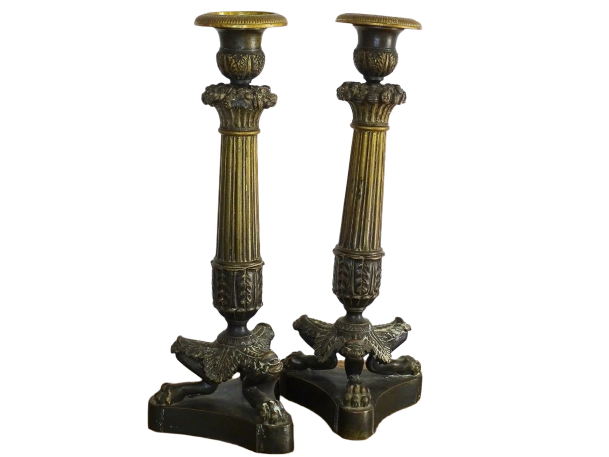 French antique bronze candle holders. French restoration period candlesticks are on a tripod base with lion paw feet and acanthus leaves. Acanthus leaves and various fruits and berries adorn the top of the reeded columns.
