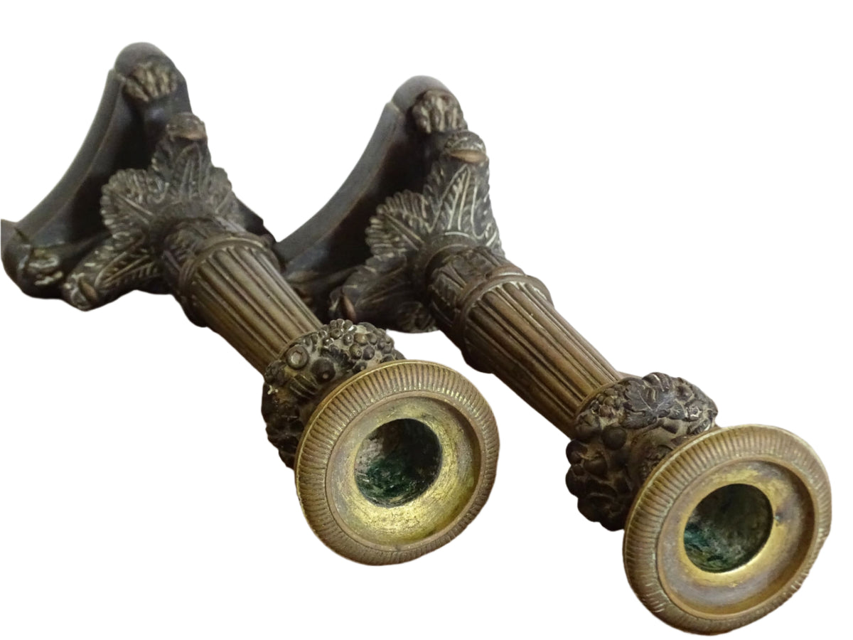 French antique bronze candle holders. French restoration period candlesticks are on a tripod base with lion paw feet and acanthus leaves. Acanthus leaves and various fruits and berries adorn the top of the reeded columns.