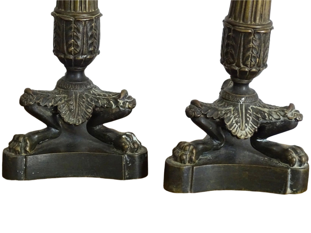 French antique bronze candle holders. French restoration period candlesticks are on a tripod base with lion paw feet and acanthus leaves. Acanthus leaves and various fruits and berries adorn the top of the reeded columns.