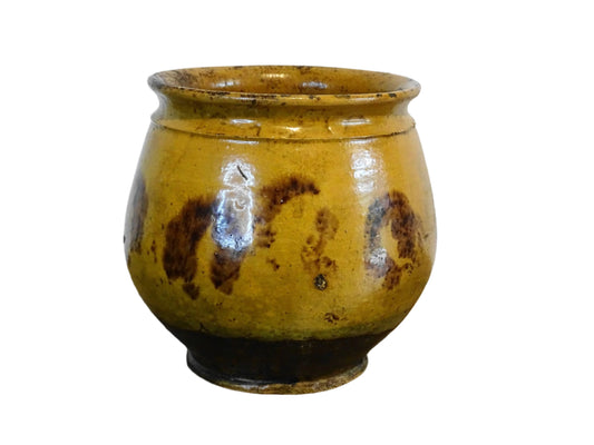 French antique ceramic confit pot with a deep yellow glaze and brown highlights. Earthenware vessel, with a rounded shape.