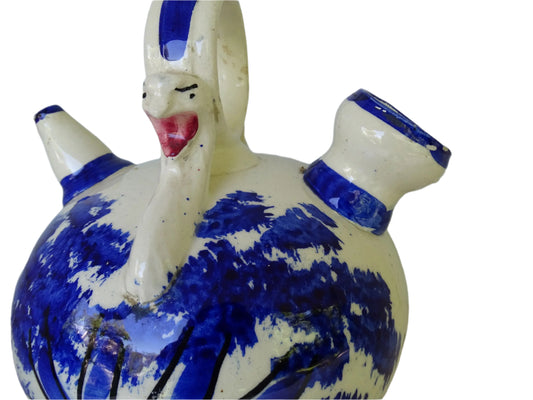 Spanish vintage blue and white ceramic gargoulette. This pottery water pitcher is hand-painted with trees and the figure of an animal. It has a handle to the top with faces to each side, as well as two spouts.