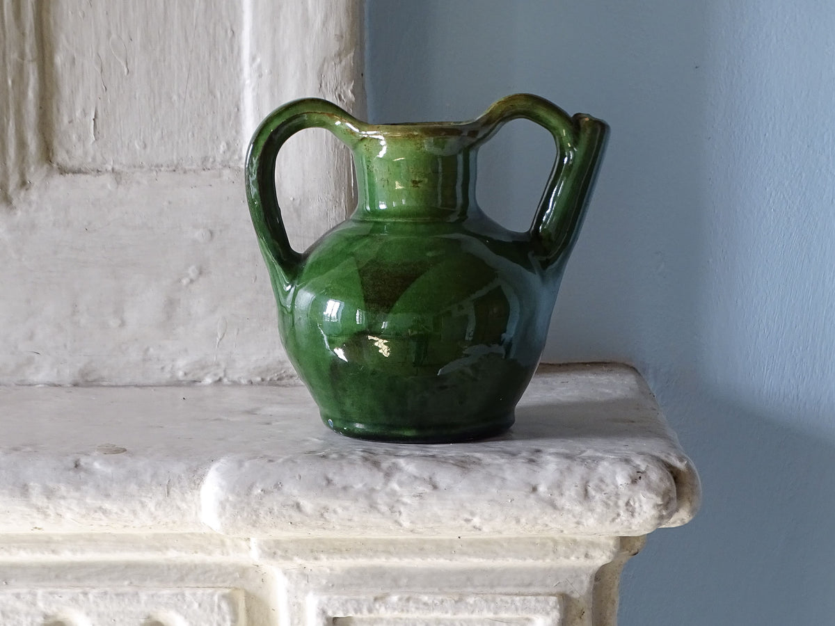 French vintage ceramic orjol jug with green glaze on an old country house fireplace