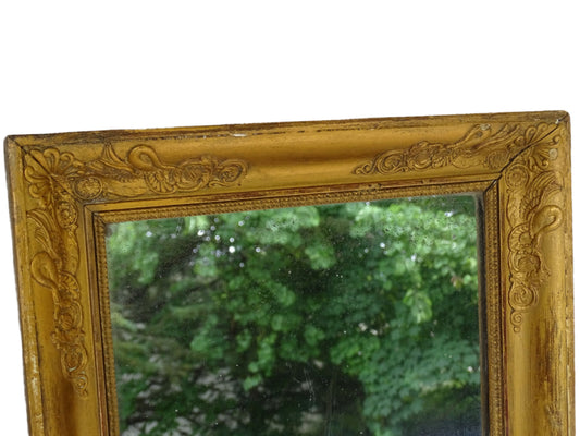 Antique French mirror with a gold wooden frame decorated with swans and ornate detailing, dating to the restoration period. There is foxing to the glass and timeworn appearance.