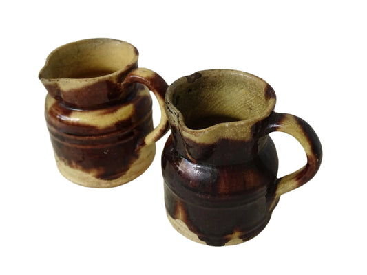 Small pair of French antique ceramic pitchers with a brown drip glaze on a yellow glazed background. These Dieulefit pottery pitchers have handles to the side.