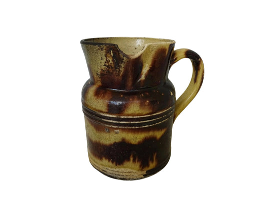 French antique pottery jug with a brown drip glaze on a yellow glazed background. This glazed ceramic pitcher has a handle to the side and would have been used for cooking.